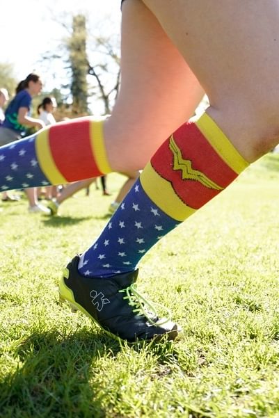 A Wellesley College student with cleats and Wonder Woman stockings on runs across a green playing field