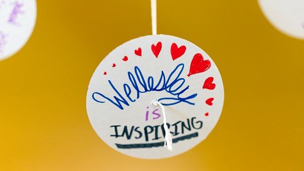 A still photo of a button adorned with hearts that reads "Wellesley is Inspiring"