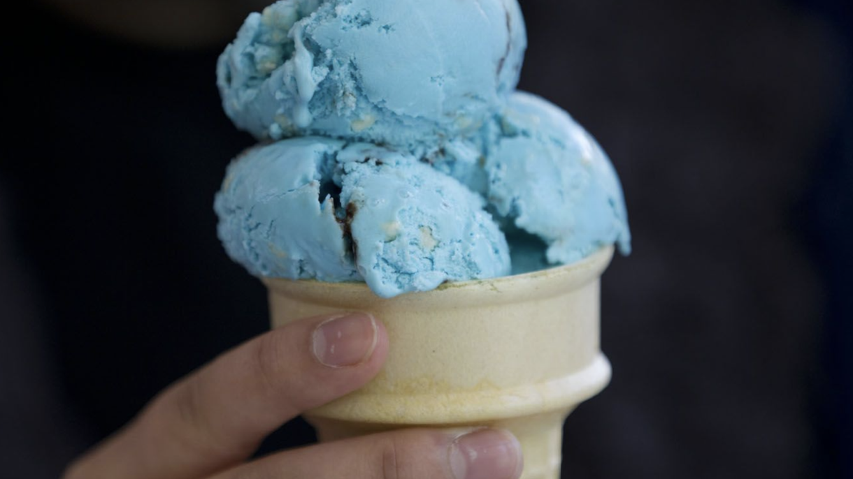 Person holding cone of blue ice cream.