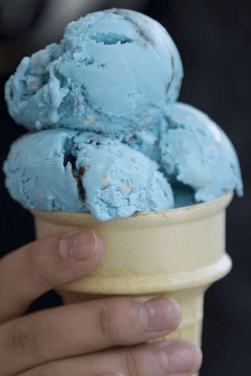 Person holding cone of blue ice cream.