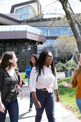 A group of Wellesley College students walk with the Lulu Chow Wang Campus Center in the background