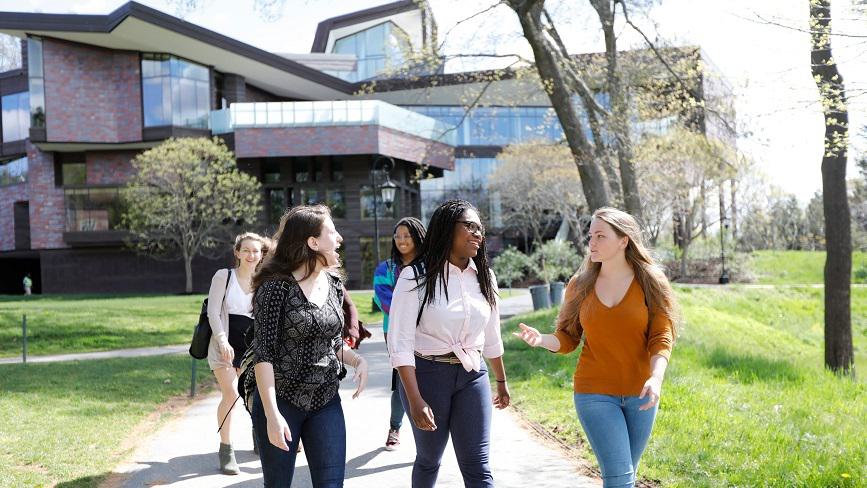 A group of Wellesley College students walk with the Lulu Chow Wang Campus Center in the background