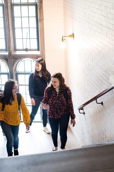A group of students walk up a steps in Wellesley College's Green Hall