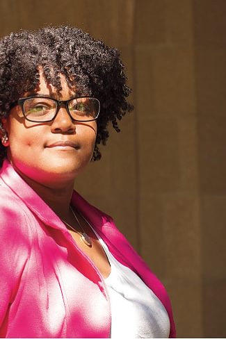 Wellesley College alumna, Serenity Hughes, smiles for a portrait, wearing a pink blazer