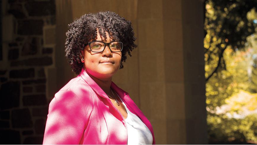 Wellesley College alumna, Serenity Hughes, smiles for a portrait, wearing a pink blazer