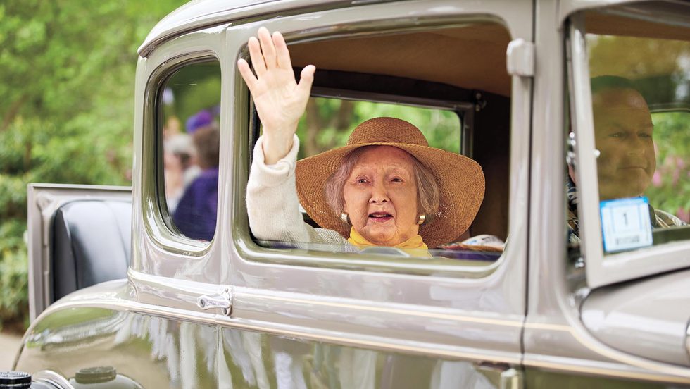 A member of the class of 1955 waves from an antique car